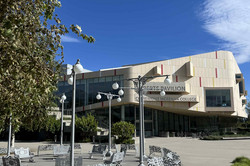 Sportzentrum Das Bild zeigt einen Park mit Sitzgelegenheiten und einem Gebäude einer Universität im Hintergrund.