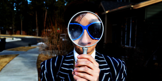 Searching Eine Person hält eine Lupe ans Auge