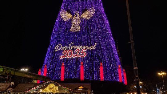 A big lit-up Christmas tree with an angel and Dortmund 2025 written on it.