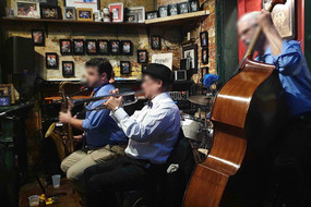 Eine kleine Jazzband, bestehend aus drei Personen, spielen Instrumente.
