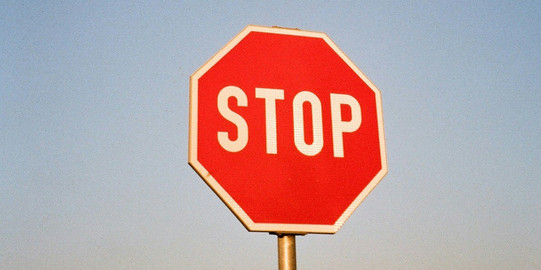 Verkehrsschild "STOP" vor blauem Himmel
