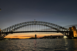 Es zeigt eine beleuchtete Brücke über dem Meer in der Abenddämmerung