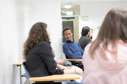 Some international students are sitting together and talking. One student laughs.