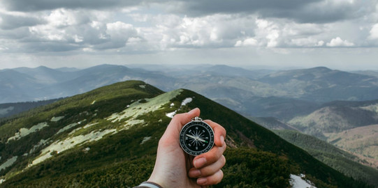 Compass A hand is reacching out in front of the camera and holding a compass