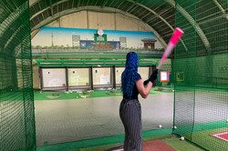 Baseball Dagny steht in einem Batting Center in Asakusa und versucht einen Ball zu treffen, der aus einer Maschine fliegt.