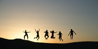 Storyteller.jpg 6 Menschen springen auf einem Berg beim Sonnenuntergang