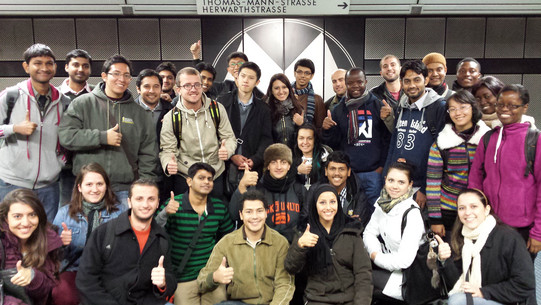 Eine Gruppe internationaler Studierender in der U-Bahn, die Daumen hoch zeigen