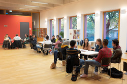 International students sit at group tables in the IBZ and talk.