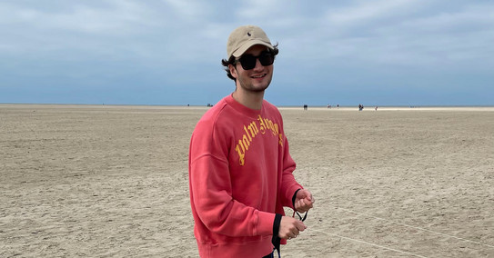 Eine Person ist am Strand und lächelt in die Kamera.