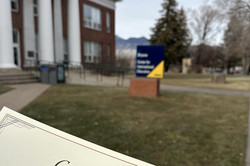 Eine Urkunde wird in der Hand gehalten - im Hintergrund ist der Campus der NAU zu sehen