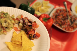 Im Vordergrund ein Teller mit Gemüse und Tortilla Chips, im Hintergrund Paprika, Zitronen und Gemüse beim beim Internationalen KulturCafé (IKC)