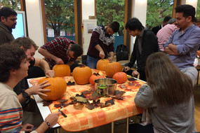 Eine Gruppe internationaler Studierender, die für Halloween Kürbisse schnitzen im Internationalen Begegnungszentrum (IBZ)