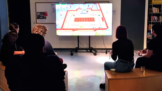 Menschen sitzen vor einem großen Bildschirm und spielen Videospiele.