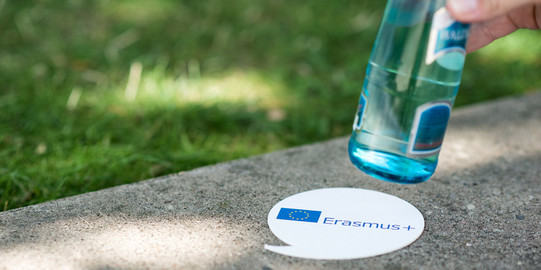 Ein Untersetzer mit dem Schriftzug "Erasmus+" unter einer Flasche Wasser