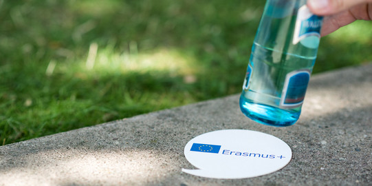 drink coaster Erasmus+ A drink coaster with the word "Erasmus+" under a bottle of water
