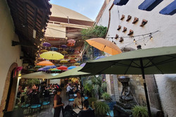 Café in Thlaquepaque Hier sieht man ein kleines Cafè mit Außenbereich, über dem Lichterketten und bunte Regenschirme hängen.