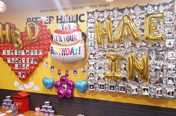 Man sieht eine Wand mit Geburtstagsballons und Bildern.