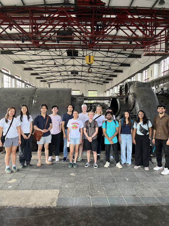 Gruppenbild internationaler Praktikant*innen in einem industriellen Gebäude.