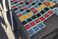 Verschiedene Beeren in kleinen Körben auf einem Marktstand. 