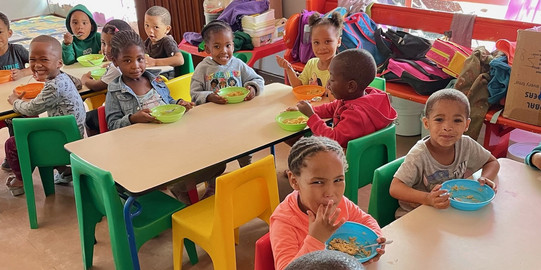 Kinder sitzen an Tischen und essen