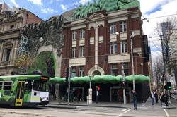 RMIT Gebäude Hier sieht man ein Gebäude des RMIT, das mit grünen Ornamenten, die wie Wolken geformt sind, gestaltet ist.