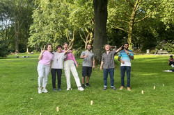 In the picture is a group of people that is playing Kubb.
