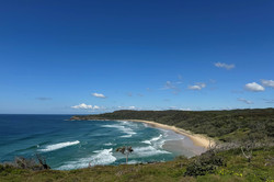 Meer Es zeigt eine große Grünfläche, im Hintergrund ist das wellige Meer und der Strand.