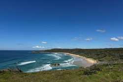 Es zeigt eine große Grünfläche, im Hintergrund ist das wellige Meer und der Strand.