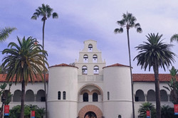SDSU Campus Auf dem Bild erkennt man ein großes Gebäude in weiß. Rechts und links neben dem Gebäude steht jeweils eine Palme.