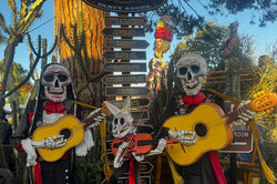 Old Town Man erkennt zwei Figuren mit Totenköpfen, die bunt geschmückt sidn und eine Gitarre in der Hand halten.