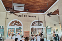 Café du Monde Hier sieht man das entsprechende Café. Es sind viele Menschen an zahlreichen Tischen zu sehen.
