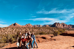 Gruppe von Freunden in der Wüste mit Bergen im Hintergrund und blauem Himmel