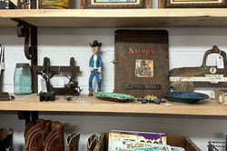 Drei Regalbretter mit Antiquitäten im Western-Stil, wie Cowboystiefel, Bilderrahmen und Kennzeichen. 