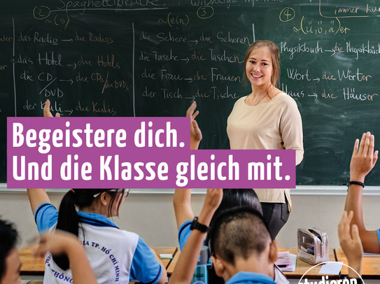 Lehramt.International - Begeistere dich (square) A woman is standing in front of a class of young children. The following text is written on the picture: "Begeistere dich. Und die Klasse gleich mit." (Get yourself excited. And the class will be too.)