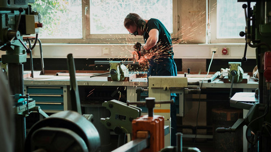 A man is welding or sawing and sparks are flying.