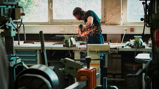 Ein Mann schweißt oder sägt und es fliegen Funken. 