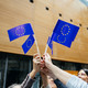 EU Flaggen Menschen stehen in einem Kreis und halten kleine EU-Flaggen in der Luft.