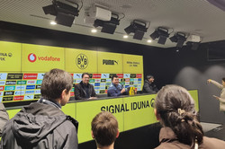 Menschen im Presseraum eines Fußballstadions.