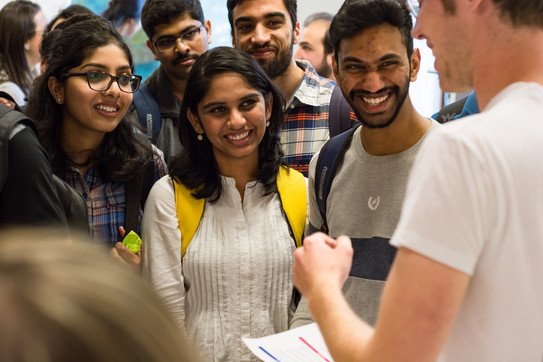 smiling international students to whom something is explained 