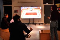 Menschen sitzen vor einem großen Bildschirm und spielen Videospiele.