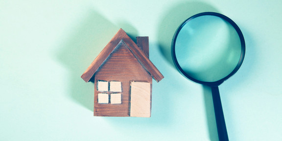 A wooden model of a house and a magnifying glass.