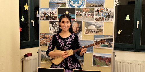 an Asian woman playing the guitar at the International CultureCafé (IKC)