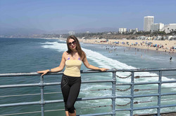 Ela Santa Monica Pier Das Bild zeigt eine Person auf einem Steg sowie den Teil eines Strandes und Meeres im Hintergrund.