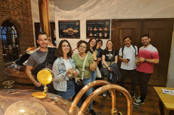 People standing in front of the copper kettles of a brewery.