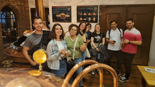 Menschen stehen vor den Kupferkesseln einer Brauerei.