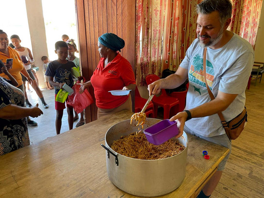 Steenvliet Soup Kitchen Man preparing plates with food for children waiting