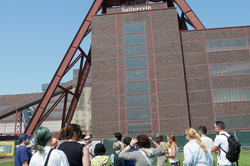Menschen stehen vor dem Förderturm der Zeche Zollverein.
