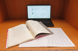Kanji-Übung Auf dem Bild sieht man ein Laptop und ein Buch.