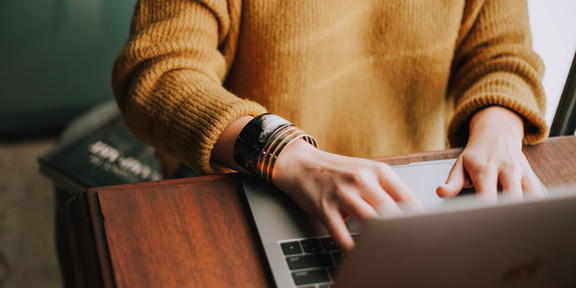 person is sitting at a laptop