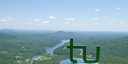  TU Logo on binoculars with a view on a river landscape
